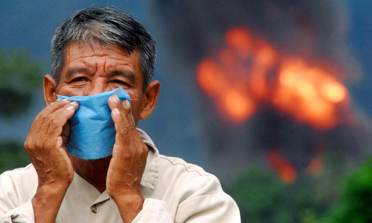 A man wears a face mask to protect himself from the fumes near the site of an explosion at a gas pipeline belonging to state oil monopoly Pemex near Olmeaca