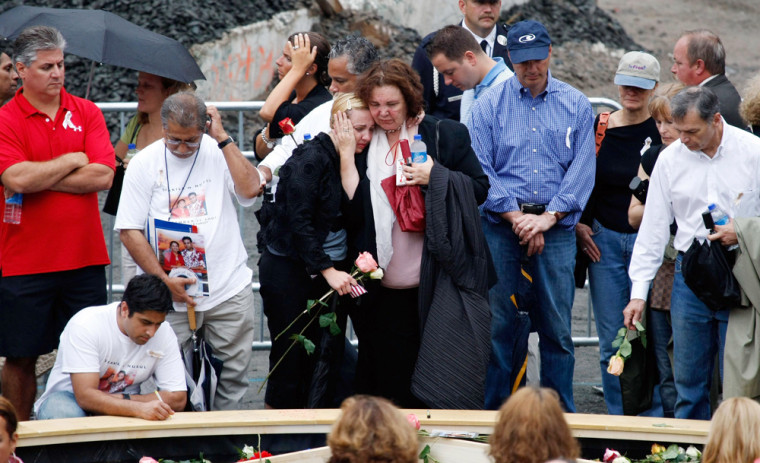 Families of victims mourn and drop flowers into a reflecting pool at the World Trade Center in New York