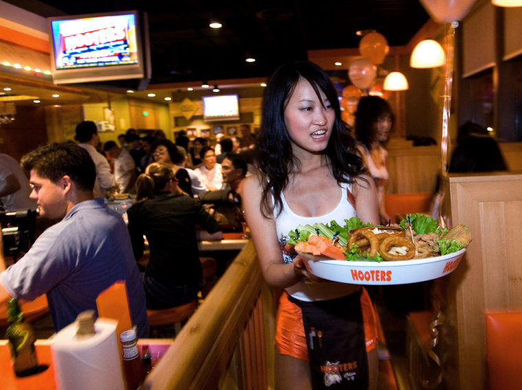 A Hooters server — wearing the now-famous clingy low-cut tank tops and high-cut shorts — delivers food on the opening day of the Beijing restaurant. 