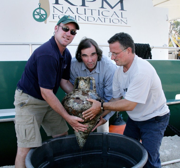 Albanian archaeologist Adrian Anastasi right, U.S. archaeologist George Robb, center, and dive master Howard Phoenix hold an alleged 2,400-year-old Greek jar, in Saranda harbor, on Aug. 14, 2007.