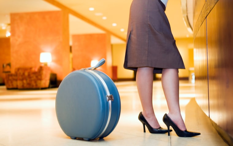 Businesswoman's legs and suitcase at a hotel front desk