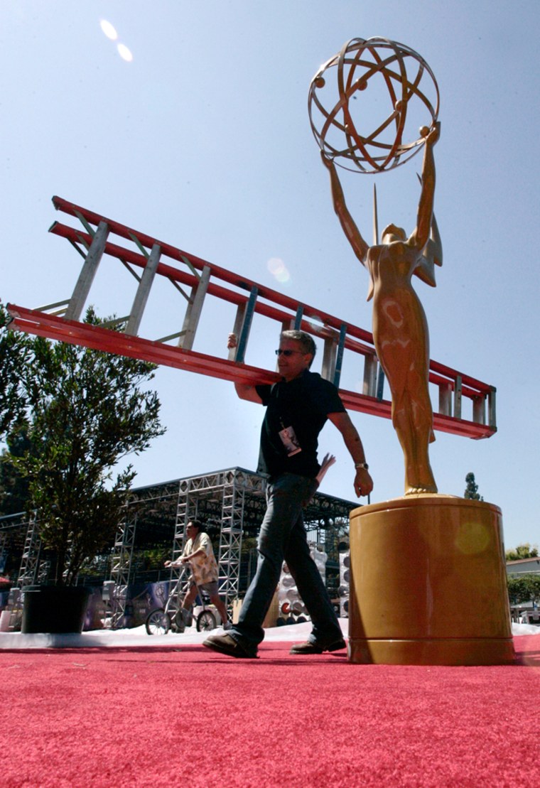 Workman Bill Delia carries a ladder passed an Emmy statue on the red carpet made with recycled products during preparations for the 59th annual Primetime Emmy Awards outside the Shrine Auditorium in Los Angeles.