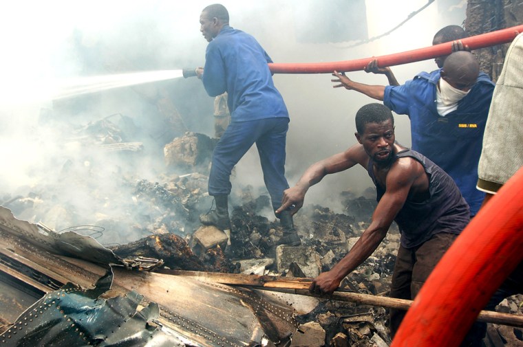 A rescue worker points out a body among the wreckage of a cargo plane that crashed Thursday in Kinshasa, Congo.