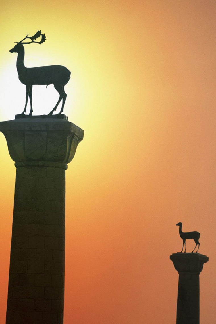 Stag and doe statues on columns guarding harbor entrance by St. Nicolas Fortress in Rhodes, Greece.
