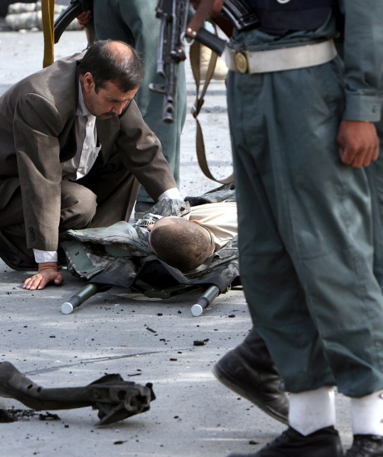 An Afghan man looks after a wounded U.S. solider shortly after a suicide car bomber attacked an American military convoy in Kabul, Afghanistan, on Saturday, Oct. 6, 2007. A suicide car bomber attacked an American military convoy in Kabul on Saturday, wounding two people and damaging dozens of shops. (AP Photo/Musadeq Sadeq)