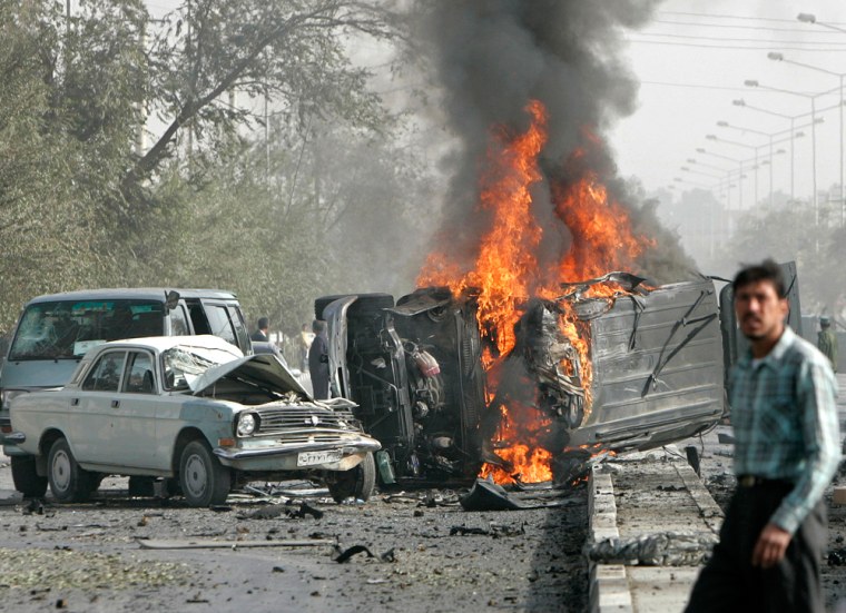 A man walks past a burning vehicle of a U.S. convoy in Kabul