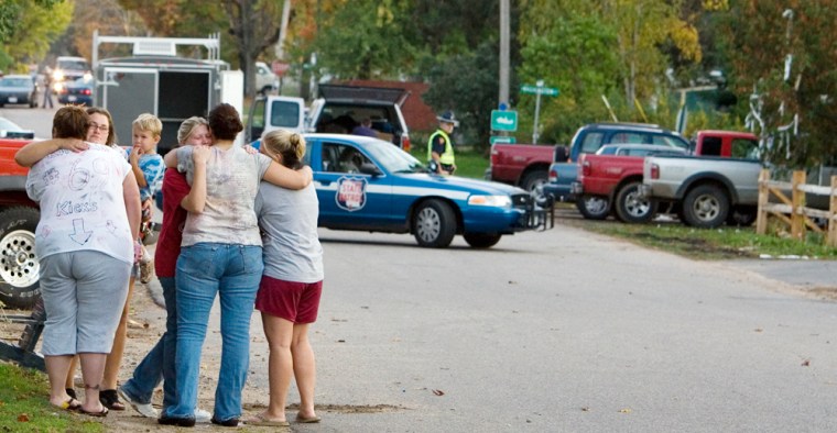 Neighbors in Crandon, Wis., gather and hug near where a sheriff's deputy went on a shooting rampage Sunday.