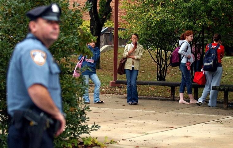 A police officer stands guard as students of Plymouth-Whitemarsh High School in Whitemarsh Township, Pa., wait to be picked-up Thursday after the arrest of a teen suspected of plotting to attack the school.