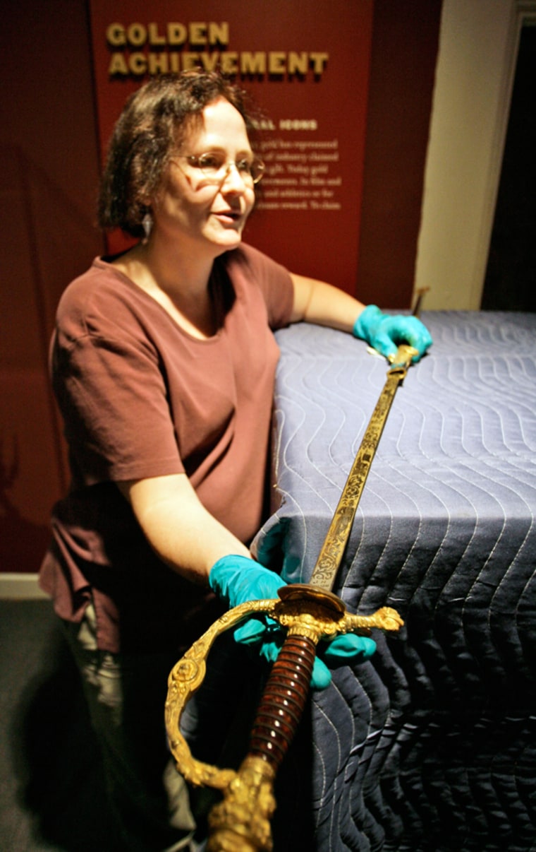 Sue Fischer, curator of material culture for the Louisiana State Museum, holds a presentation sword that will be part of the "Gold" exhibit at the Old U.S. Mint in New Orleans.