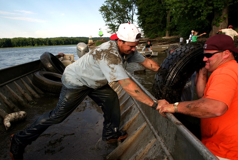 Cleanup crusader Chad Pregracke, left, helps a volunteer load river junk onto a boat. His campaign to remove garbage from parts of the upper Mississippi has attracted a legion of volunteers, won Pregracke a presidential award and garnered corporate sponsorship.