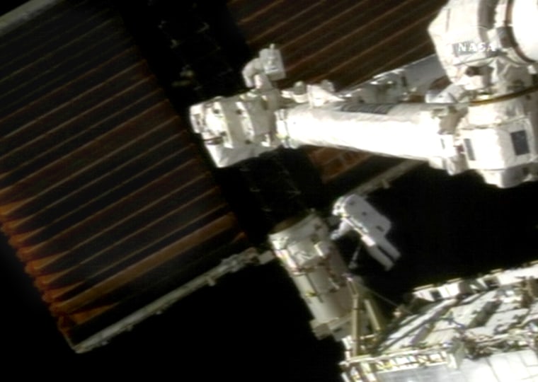 Swedish astronaut Christer Fuglesang can be seen working on the base of a stuck solar array during Monday's spacewalk. The joints of a robotic arm can be seen in the foreground, above Fuglesang.