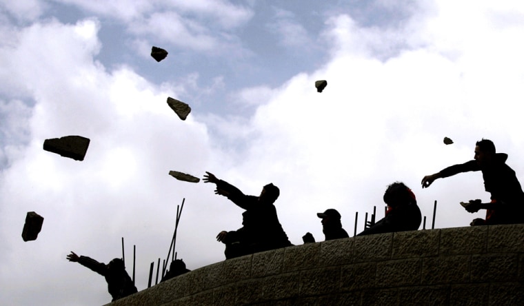 Palestinians throw stones at Israeli military vehicles, not seen, during an Israeli army operation in the West Bank City of Nablus, Sunday Feb. 25 2007. Dozens of Israeli jeeps and armored vehicles raided the West Bank city of Nablus Sunday and placed tens of thousands of Palestinians under curfew. (AP Photo/Emilio Morenatti)
