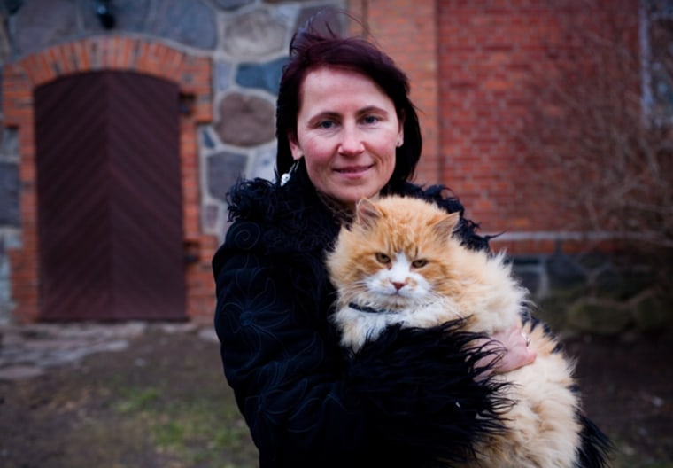 Writer and filmmaker Laima Muktupavela holds her cat Rudijs outside her home in rural northeastern Latvia.