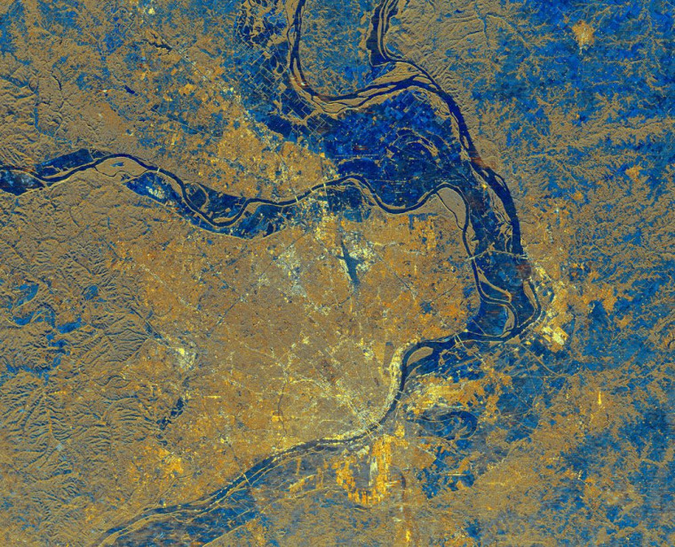 This is a spaceborne radar image of the area surrounding St. Louis, Missouri, where the Mississippi and Missouri Rivers come together. The city of St. Louis is the bright gold area within a bend in the Mississippi River at the lower center of the image. The rivers show up as dark blue sinuous lines. Urbanized areas appear bright gold and forested areas are shown as a brownish color. The Missouri River flows east, from left to right, across the center of the image, and meets the Mississippi River, which flows from top to bottom of the image.