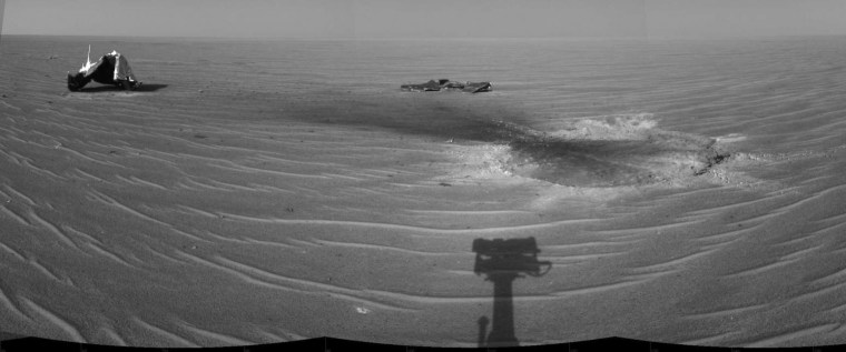 NASA's Mars Exploration Rover Opportunity gained this view of its own heat shield during the rover's 325th martian day (Dec. 22, 2004). The main structure from the successfully used shield is to the far left. Additional fragments of the heat shield lie in the upper center of the image. The heat shield's impact mark is visible just above and to the right of the foreground shadow of Opportunity's camera mast. This view is a mosaic of three images taken with the rover's navigation camera.