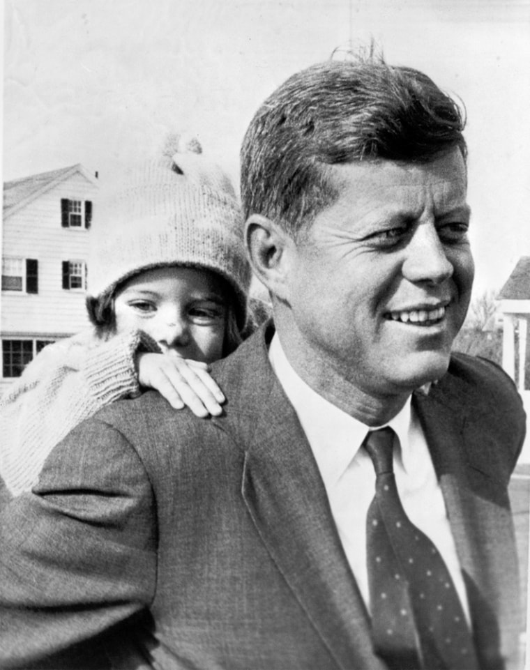 Caroline Kennedy peeps over the shoulder of her father, Senator John F. Kennedy, as he gave her a piggy-back ride November 9, 1960 at the Kennedy residence in Hyannis Port, Mass. It was the first chance hard-campaigning Kennedy has had to relax with his daughter in weeks. (AP Photo)