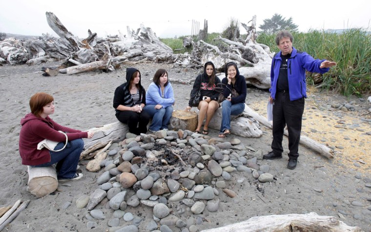 ** ADVANCE FOR SUNDAY, SEPT. 21 ** Visitors listen Friday, Sept. 5, 2008, to Michael Gurling, right, of the Forks, Wash., Chamber of Commerce, talk about the bonfire location on a beach in LaPush, Wash., that is portrayed as the place where Bella Swan, the main character in author Stephenie Meyer's vampire-themed \"Twilight\" books, learns that her high-school friend Edward Cullen is really a vampire. The visitors were taking part in a \"Twilight Tour\" led by Gurling that takes fans of the books, which are set in the nearby town of Forks, Wash., around to locations central to the plot and characters. The attention is welcome in Forks, which has long suffered by the decline in the timber industry. (AP Photo/Ted S. Warren)