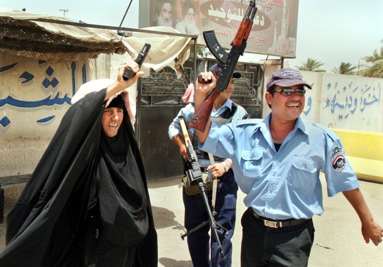 Iraqi police officers and an elderly woman fire guns in the air to celebrate the news that Abu Musab al-Zarqawi, al-Qaida's leader in Iraq who led a bloody campaign of suicide bombings and kidnappings, has been killed in an air raid north of Baghdad, in the Sadr City area of Baghdad, Iraq Thursday, June 8, 2006. One of the police officers gave his pistol to the elderly woman, whom he knew, so that she could join in the celebrations by firing in the air with them. (AP Photo/Karim Kadim)