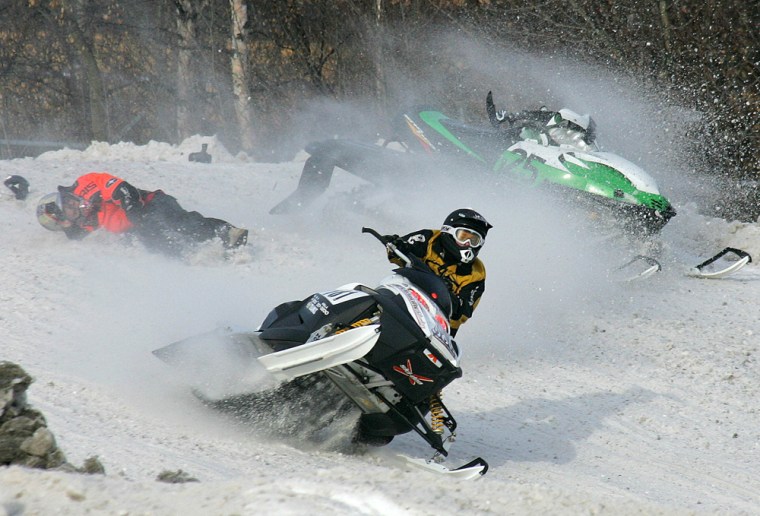 Two snowmobiles collide, knocking one rider off, as they race around the track during the Fur Rendezvous Sno-X races in Anchorage, Alaska, Saturday, Feb. 26, 2005. The 17-day winter festival includes the World Championship Sled Dog races, dog weight pull, snow sculptures and other events to break up the long Alaska winter. (AP Photo/Al Grillo)