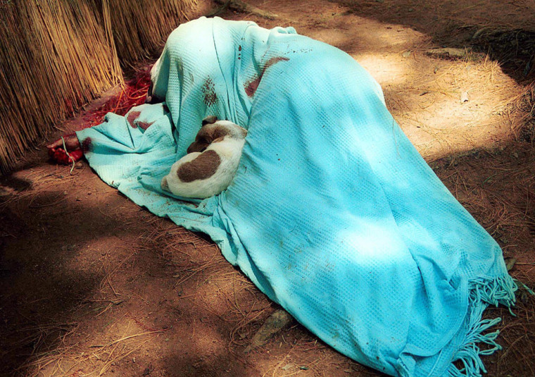 The body of Zimbabwe farmer Terry Ford lies under a blanket with his Jack Russell dog curled up on him after he was  allegedly shot dead by a group of  war veterans and farm invaders at his Gowrie farm in Norton, about 30 kilometers (20 miles) west of Harare, Monday March 18, 2002.  Ford, 51, was the 10th white farmer killed since militants began often violent occupations of white-owned land two years ago. (AP Photo)