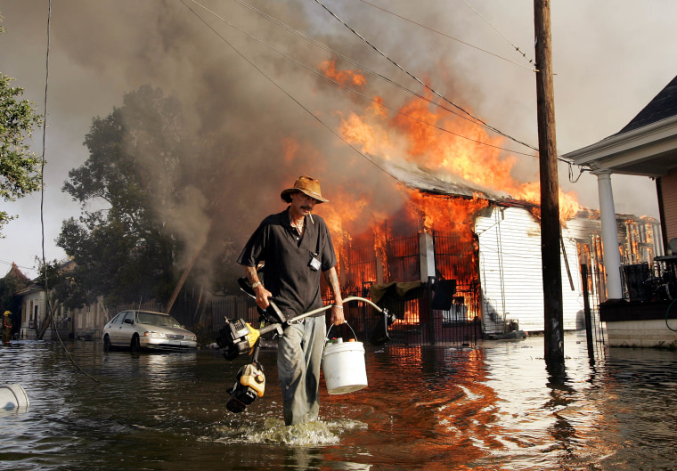 A man makes his way out of flood waters as a home burns in the seventh ward of New Orleans during the aftermath of Hurricane Katrina