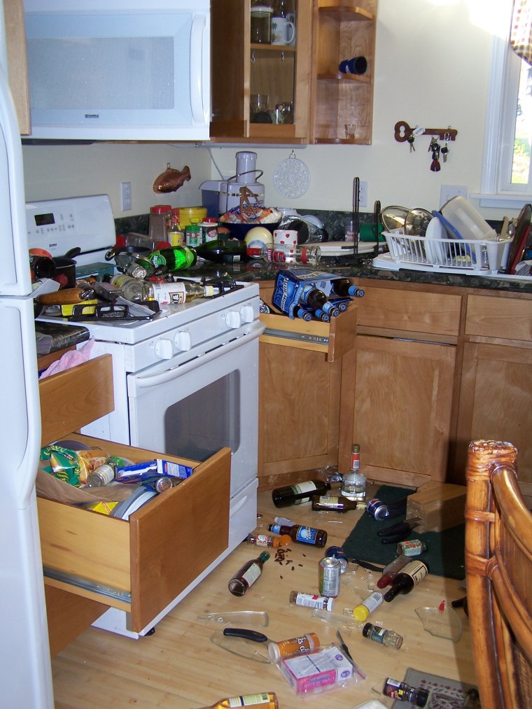 kitchen cabnets thrown open with debreis and broken glass/items