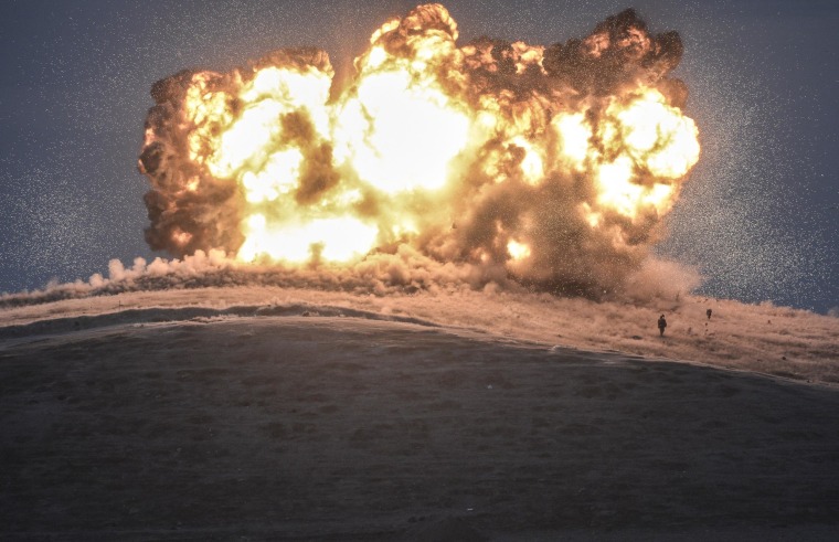 Image: An ISIS militant stands as an airstrike hits an ISIS position on Tilsehir hill near the Syrian-Turkish border on October 23, 2014.