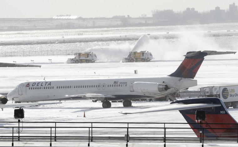 Image: Plows clear snow from a runway at JFK Airport in New York on Friday.