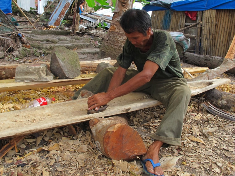 Image: Fisherman Charito Badong shapes the hard wood of a tree blown down by Typhoon Haiyan into a hull for his new fishing boat in Botlog Daku