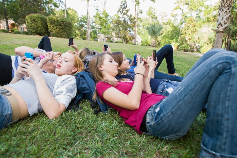 Image: Teen girls text on their phones.