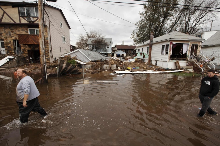 Image: Men walk through flooding left by the storm surge of Superstorm Sandy in the New Dorp Beach neighborhood of the Staten Island borough of New York