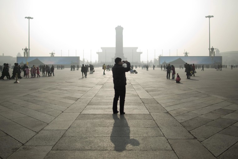 Image: A tourist takes photos during a heavily polluted day on Tiananmen Square in Beijing.