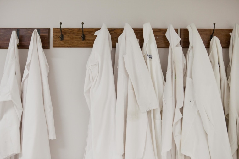 Lab coats hang in a row at a hospital. New guidance suggests that doctors and other health workers launder their coats at least once a week and hang them on hooks when they're actually examining patients.
