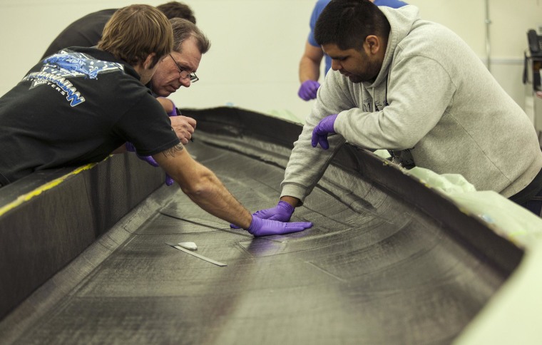 Image: Engineers apply layers of woven carbon fiber material to build a wing component of the next SpaceShipTwo craft at Virgin Galactic.