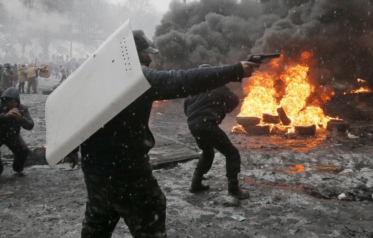 Image: A protester points a handgun during a clash with police in central Kiev, Ukraine