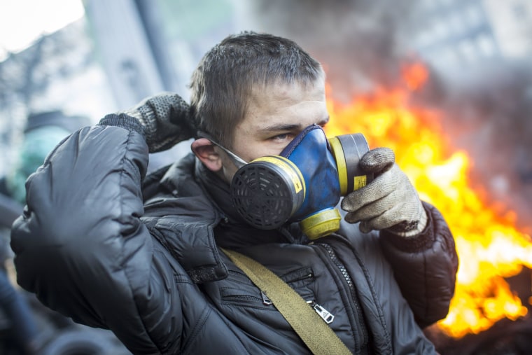 KIEV, UKRAINE - JANUARY 24: An anti-government protestor puts on a gas mask near Dynamo Stadium on January 24, 2014 in Kiev, Ukraine. Talks to resolve the political stalemate in the Ukraine have failed as anti government protests continue in the capital and opposition leader Vitali Klitschko urges the government to call a snap election. (Photo by Rob Stothard/Getty Images)