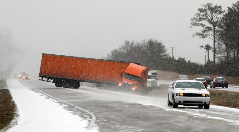 Image: A truck goes off the road into the median while trying to avoid another wrecked truck as snow begins to accumulate on I-65 in Alabama on Tuesday, Jan. 28 in Clanton, Ala.