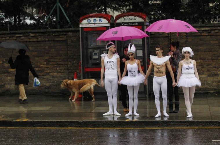 Image: Human rights campaigners dressed as ballet dancers wait to cross a road