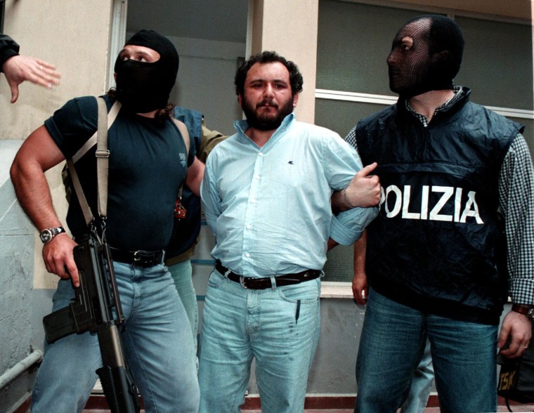 Image: Anti-Mafia police wearing masks to hide their identity, escort top Mafia fugitive Giovani Brusca May 1996.