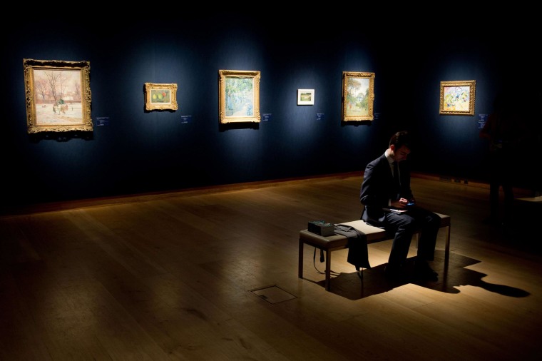 Image: A man sits among various artworks during a press call on January 30, 2014, for the "Impressionist, Modern and Surrealist Art" sale