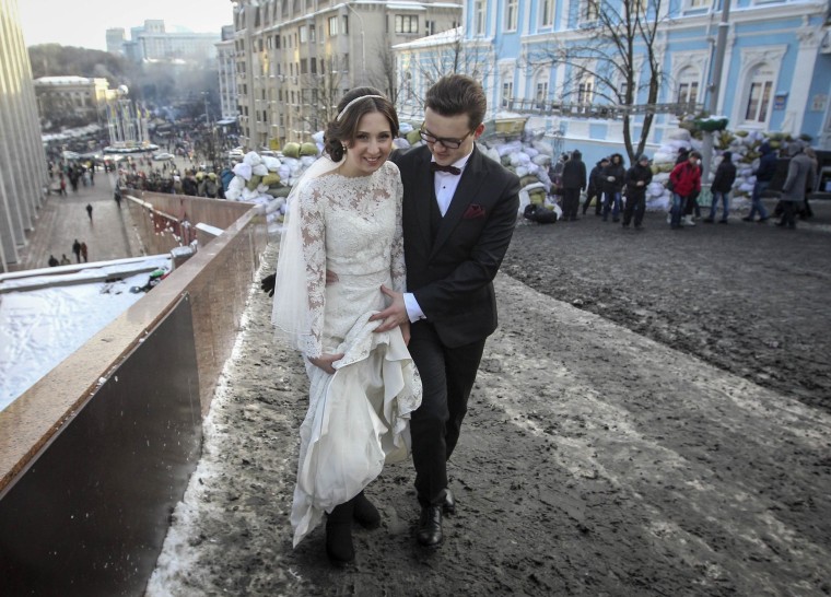 Image: A newlywed couple walks near a barricade built by anti-government protesters in Kiev