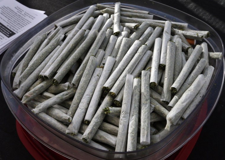 In this Oct. 2, 2013 photo, joints are piled into a container during a free pot giveaway during an anti-pot tax rally, in Denver. Colorado is making final preparations for marijuana sales to begin Jan. 1, a day some are calling "Green Wednesday." (AP Photo/Brennan Linsley)