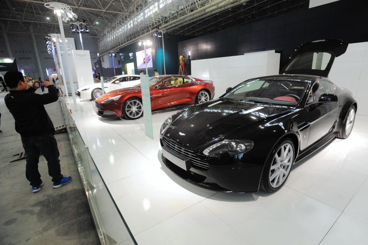 Image: Visitors take photos of Aston Martin cars at an auto show in Wuhan, China