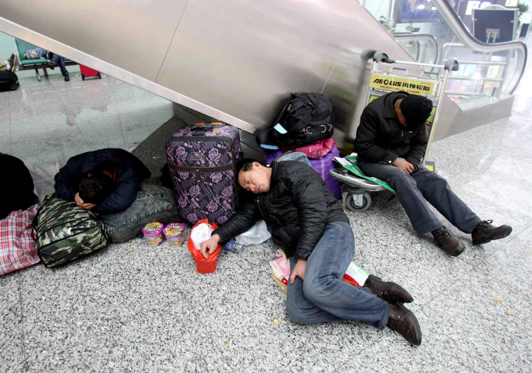 Image: Passengers sleep on their luggages after being stranded due to heavy snowfall at the Zhengzhou Xinzheng International Airport in Zhengzhou