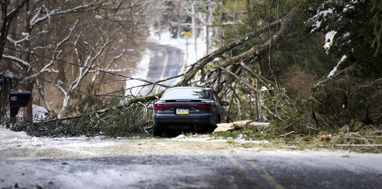 Image: An abandoned car and a tree limb that took out a utility line block a road in the aftermath of a winter storm