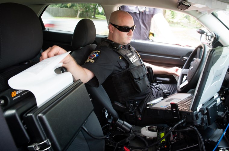 Image: Officer Jeff Innocenti, pulls a ticket from his printer, during a traffic stop