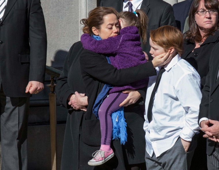 Image: O'Donnell holds her daughter Willa as she touches the head of their son Cooper while casket arrives for the funeral of actor Philip Seymour Hoffman in the Manhattan borough of New York