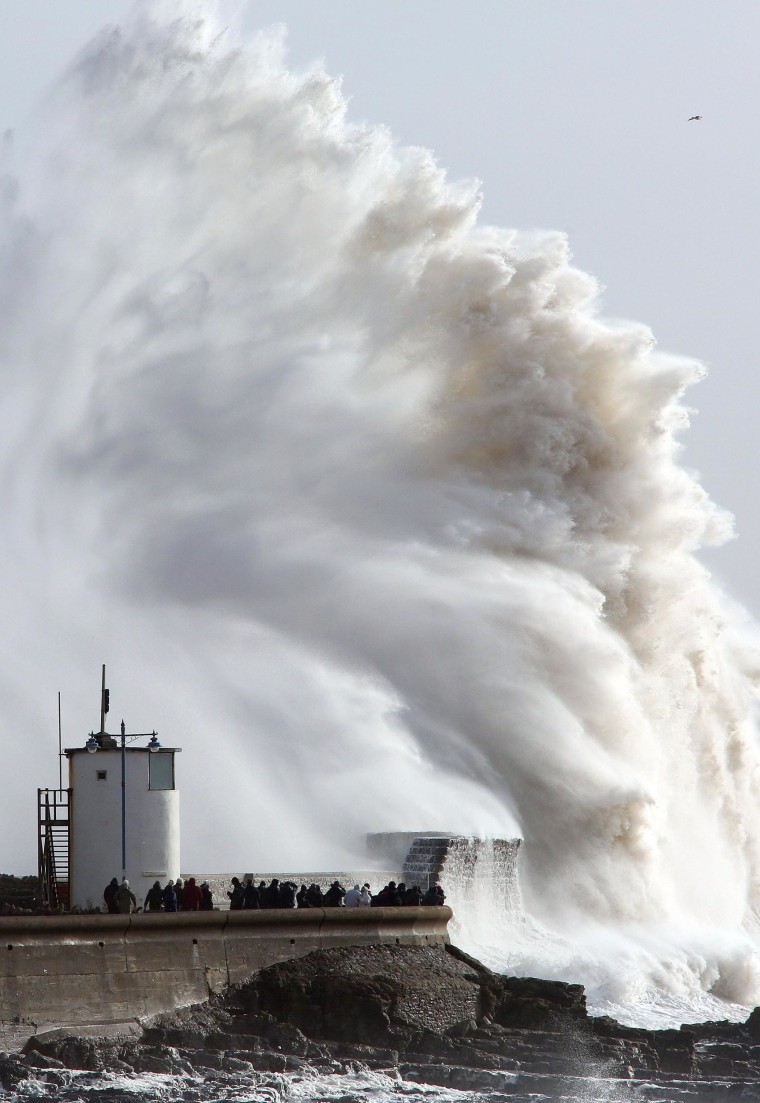 Image: People look on as high waves strike the harbour wall at Porthcawl, south Wales