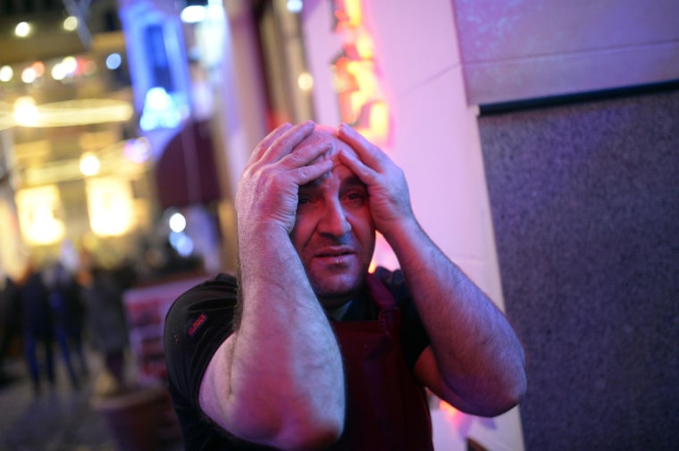 Image: A shop owner holds his head in reaction to a protest