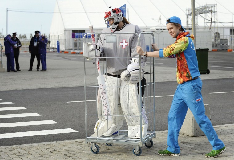Image: A volunteer transports Switzerland's women Ice Hockey team goalkeeper Florence Schelling to a practice session during the Sochi Winter Olympics on February 9, 2014.